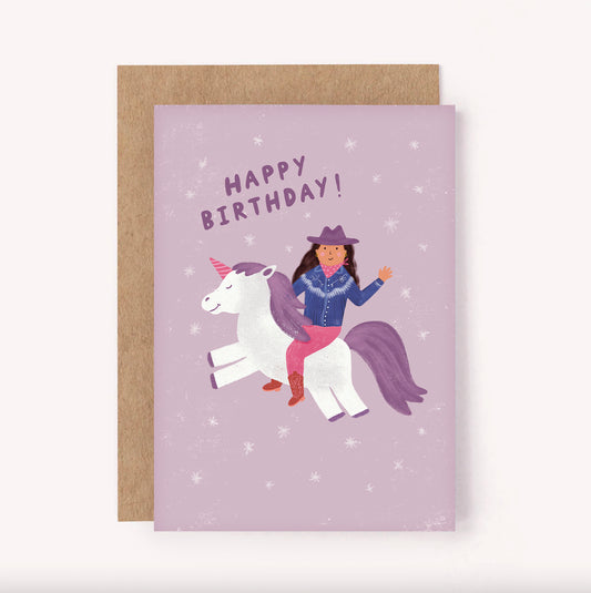 Fun, illustrated "Happy Birthday" greeting card with a cowgirl riding a unicorn, set upon a purple background