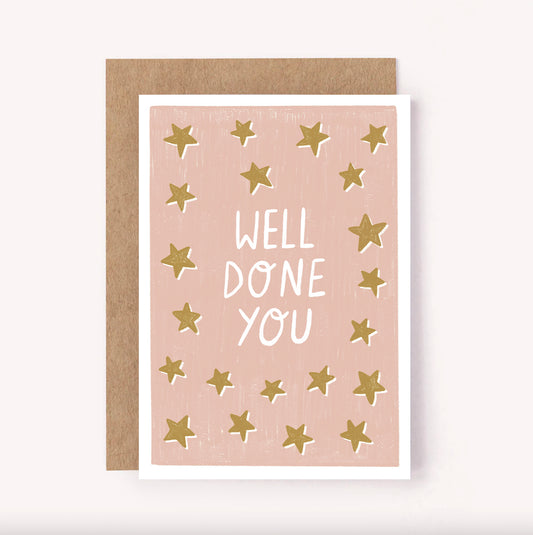 Illustrated congratulations card, featuring a hand-lettered "Well Done You" on a dusty pink background surrounded by golden stars. Perfect for celebrating a new job, passed exams, getting into Uni or more joyful occasions