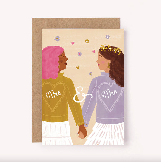 Celebrate the union between two lovely brides with this "Mrs. & Mrs." wedding greeting card. Features an illustrated couple in matching embroidered jackets, holding hands on their happy day