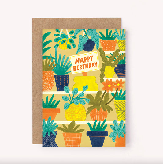 This birthday card features rows of beautiful, illustrated potted plants and hanging baskets filled with foliage. "Happy Birthday" is handwritten on a sign in bright orange